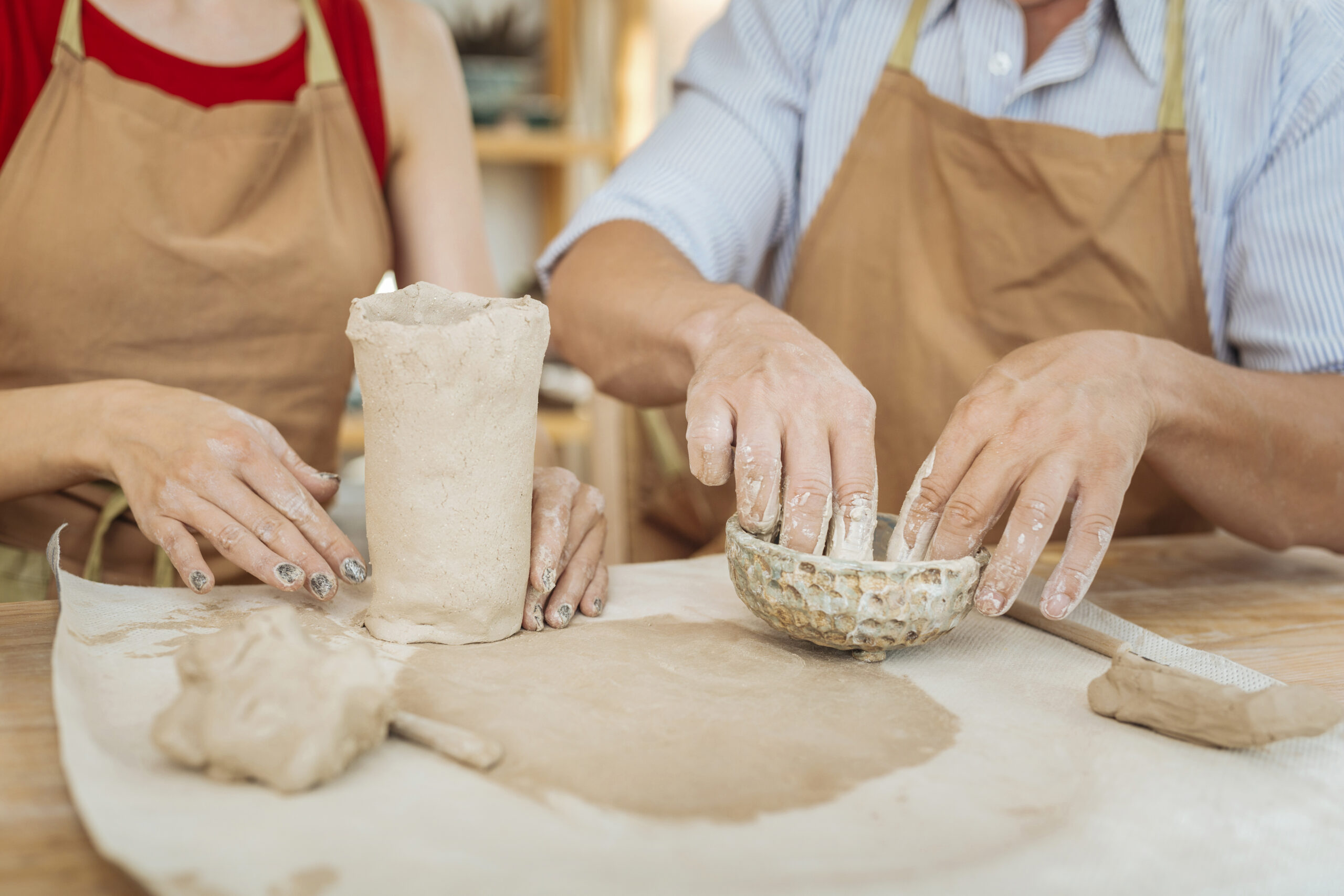 Collective work. Couple of inspired professional potters wearing brown aprons working collectively